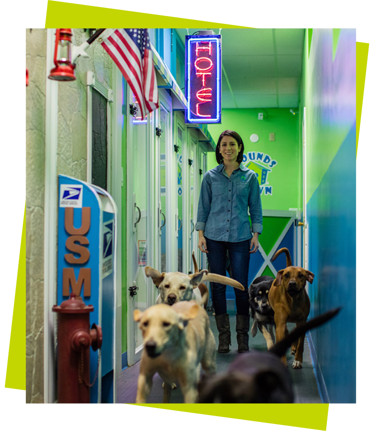 Houndstown Services Image 2 4 dogs and a smiling woman in a hallway at hounds town